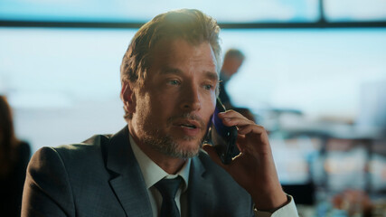 Businessman making a phone call in airport lounge