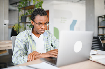 Focused university student studying on laptop in library