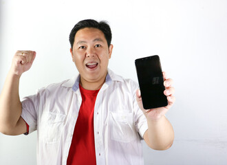 Happy Indonesian man clenched his hand and hold his mobile phone