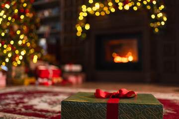 Green gift box in classical Christmas decorated interior living room library with fireplace. Christmas gift near fir tree on Christmas eve. Modern classic style interior design apartment. Christmas