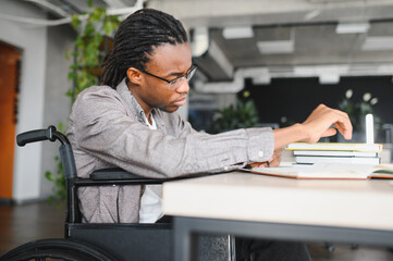 Focused african american student in wheelchair studying at desk