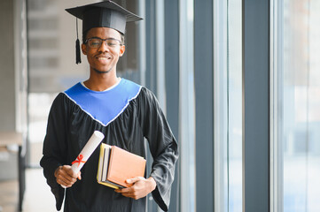 Smiling graduate student holding diploma and books at university