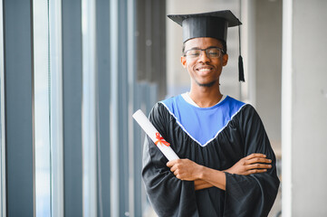 Happy african american graduate student holding diploma in university building