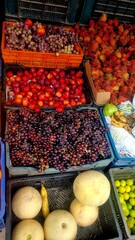 Colorful assortment of tropical fruits including guavas, limes, rambutans, bananas, grapes, and...