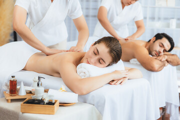 Obraz premium Caucasian couple customer enjoying relaxing anti-stress spa massage and pampering with beauty skin recreation leisure in day light ambient salon spa at luxury resort or hotel. Quiescent