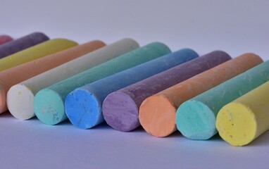 Side angle view of large pastel chalk sticks arranged in neat rows. Artistic texture and vibrant colors represent creative expression, school supplies, and children drawing tools.
