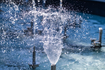 A close-up of a fountain jet forming a swirling cone of water, with dynamic splashes and droplets,...