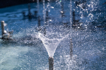 A close-up of a fountain jet forming a swirling cone of water, with dynamic splashes and droplets,...