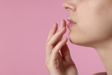 Young woman with lip balm on pink background, closeup. Space for text