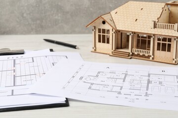 Real estate. House model and floor plan on white wooden table, closeup