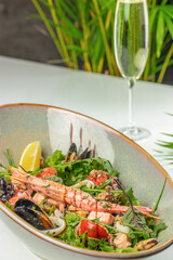 A vibrant seafood salad with shrimp, mussels, and fresh greens is served in a rustic bowl alongside...