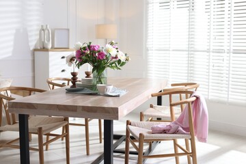 Dining table with beautiful flowers and dishware in room, space for text. Interior design