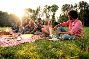 Group of multiethnic teenagers spending time outdoor on a picnic at the park