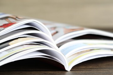 Different open magazines on wooden table, closeup