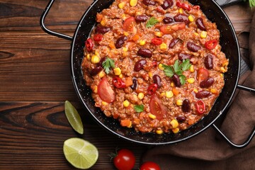 Tasty chili con carne in baking dish on wooden table, flat lay