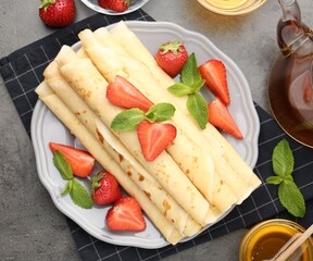 Tasty crepes with strawberries and mint on grey table, flat lay