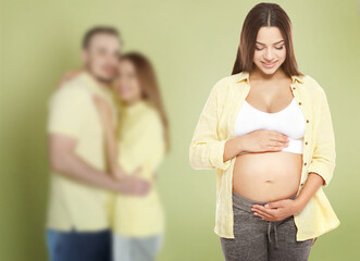 Surrogate mother and intended parents against olive color background, selective focus