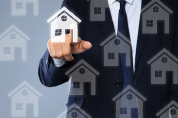 Real estate agent choosing house on virtual screen against grey background, closeup