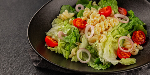 Pasta salad green leaf lettuce, tomato, pasta, onion fresh delicious gourmet food background on the table rustic food top view copy space keto and paleo diet vegan and vegetarian food