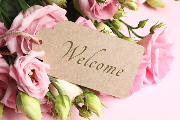 Welcome card and bouquet of eustoma flowers on pink background, closeup