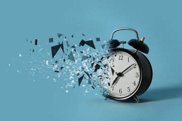 Time running out. Black alarm clock dissolving against light blue background