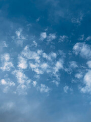 A Serene Blue Sky with Scattered White Puffy Clouds in Vertical Format