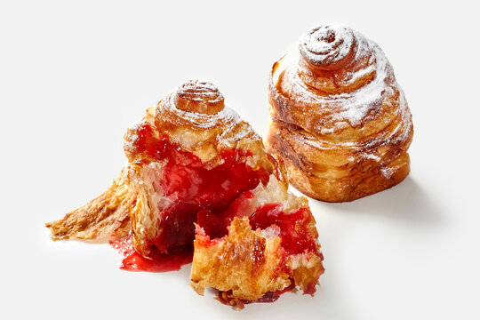 Delicious cruffin filled with strawberry jam and icing sugar on white background