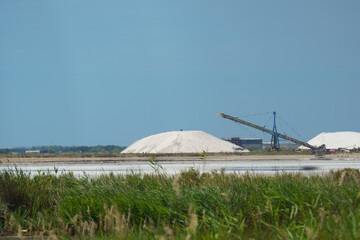 The Salin d'Aigues-Mortes salt works with pink evaporation ponds and towering white salt mountains (camelles) in the Camargue, Gard, France—ideal for industrial heritage, nature and travel photograph
