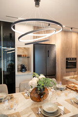A Contemporary Dining Room Featuring Minimalist Décor, an Elegant Table Setting, and a Modern Chandelier Above in a Stylish Kitchen Environment
