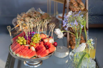 A Colorful Spread of Fresh Fruits and Floral Arrangements on an Elegant Table, Perfect for a Summer...