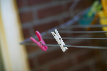 Clothespins attached to a drying line in a sunny backyard filled with colorful laundry in the...