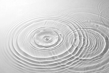 A serene and minimalist view of gentle concentric water waves expanding from two impact points,...