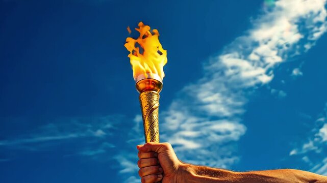 Man hand holds a torch with the Olympic flame against a blue sky background.
