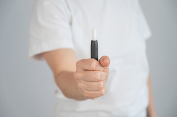 Faceless woman holding tobacco heating system. 