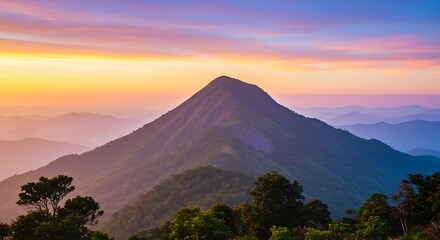 A majestic mountain peak silhouette against a vibrant and colorful sunset sky with layers of fog.