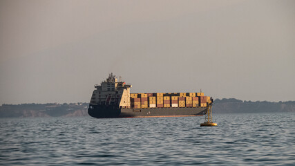 Cargo ship loadded with colorful containers sailing across the open sea.