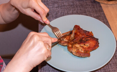 Woman cut of pieces of steak on ceramic plate. Food