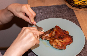 Woman cut of pieces of steak on ceramic plate. Food