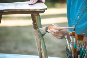 Woman  painting a wooden furniture outdoors, an eco-friendly re-use business.