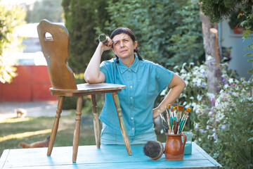 Woman  painting a wooden furniture outdoors, an eco-friendly re-use business.
