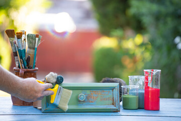 Woman painting a wooden furniture outdoors, an eco-friendly re-use business.