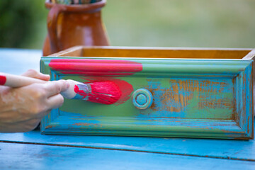 Woman painting a wooden furniture outdoors, an eco-friendly re-use business.