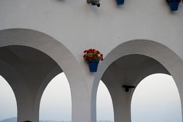 Beautiful geraniums in blue pots adorn the arches of an old building in Málaga, Spain during sunset