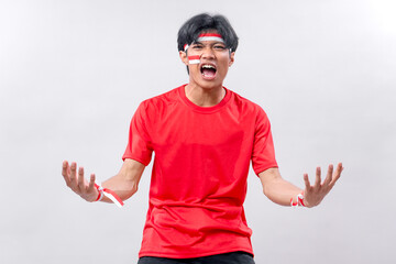 Young Indonesian man with face paint, red shirt, and expressive pose shouting with passion....