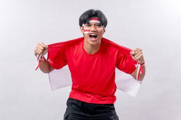 A young Indonesian man enthusiastically celebrates Independence Day, pulling the Indonesian flag...