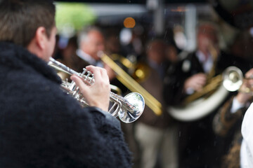 Musicians performing with brass instruments during an outdoor event on a rainy day in a lively city...
