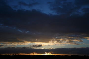 Beautiful sunset over a tranquil landscape with dramatic clouds in the evening sky