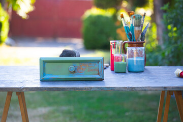 Painting a wooden furniture outdoors, an eco-friendly re-use business.