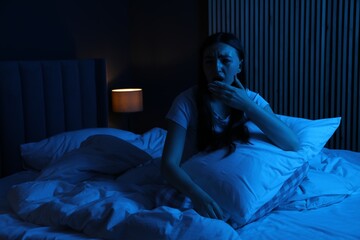 Frustrated woman with pillow suffering from insomnia on bed at home