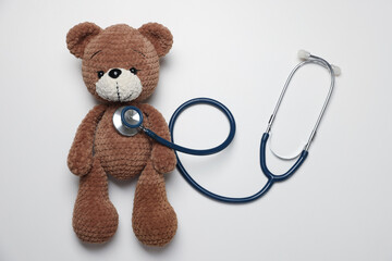 Pediatrics concept. Toy bear with stethoscope on white background, top view